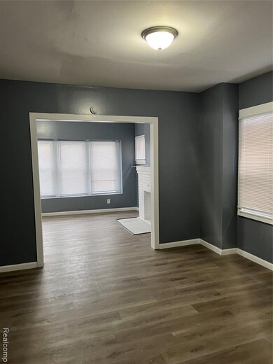 Empty room with dark wood-style floors and a brick fireplace