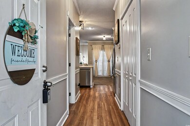 Corridor with dark wood finished floors, a textured ceiling, and crown molding