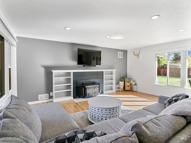 Living room featuring light wood finished floors, recessed lighting, and a wood stove