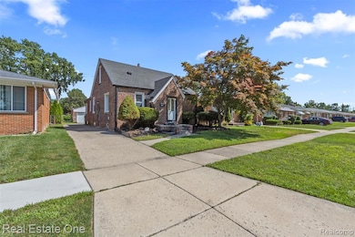 View of front of home with an outdoor structure, brick siding, and a front lawn
