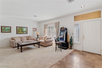 Living room with recessed lighting, light stone finish floors, and light colored carpet