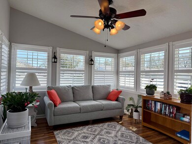 Sunroom / solarium featuring a healthy amount of sunlight, custom plantation shutters and lofted ceiling