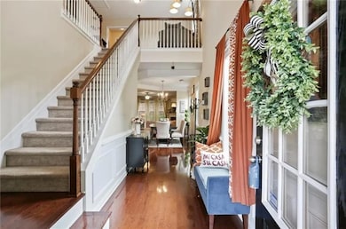 Foyer entrance with wood finished floors, a chandelier, stairway, and a towering ceiling