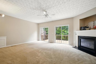 Unfurnished living room with a ceiling fan, carpet, a glass covered fireplace, baseboards, and a textured ceiling