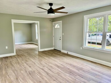 Foyer with baseboards, plenty of natural light, light wood finished floors, and a textured ceiling