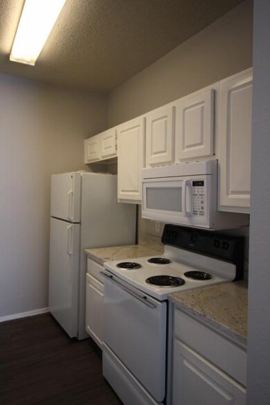 Kitchen with white cabinetry, stove, baseboards, 