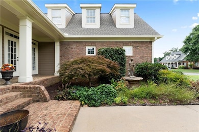 Entrance to property with roof with shingles, a porch, and brick siding