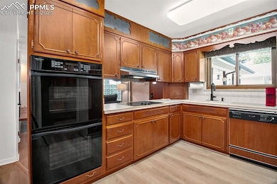 Kitchen with brown cabinetry, dishwasher, light wood-style flooring, and light countertops