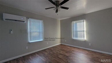 Unfurnished room with dark wood-type flooring, a wall mounted air conditioner, and a ceiling fan