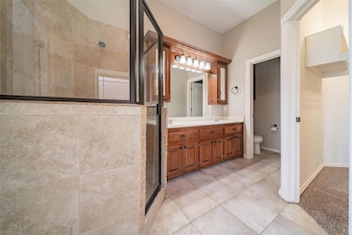 Bathroom with toilet, a stall shower, double vanit