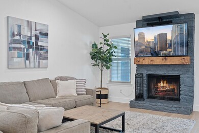 Living room with wood finished floors, a stone fi