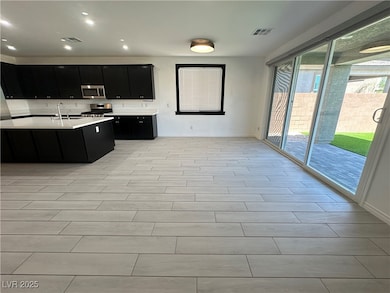 Kitchen with dark cabinets, appliances with stainl
