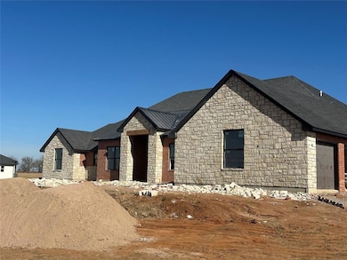 View of front facade with stone siding, a metal roof, a standing seam roof, and a garage