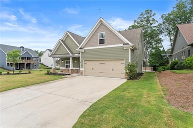 Craftsman inspired home featuring a front lawn, a porch, driveway, stone siding, and an attached garage