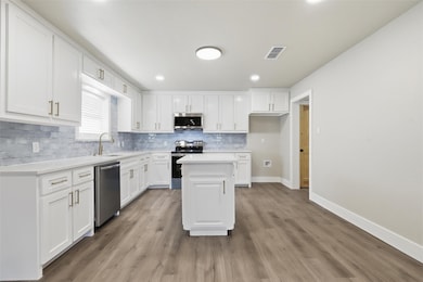 Kitchen with white cabinetry, stainless steel appliances, light wood-type flooring, and recessed lighting
