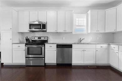Kitchen with light stone counters, white cabinets,