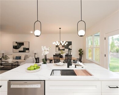 Kitchen with light stone countertops, stainless steel dishwasher, white cabinets, pendant lighting, and open floor plan