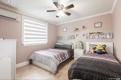 Bedroom featuring crown molding, wood finished floors, an AC wall unit, and a ceiling fan