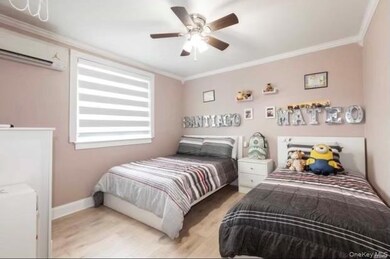 Bedroom featuring crown molding, wood finished floors, an AC wall unit, and a ceiling fan