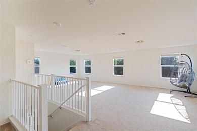 Hallway with an upstairs landing, plenty of natural light, and light carpet