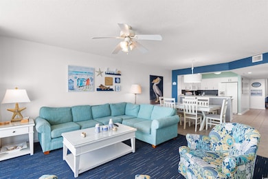 Living area featuring ceiling fan and a textured ceiling