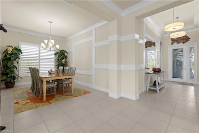 Dining room with ornamental molding, light tile patterned floors, and a chandelier
