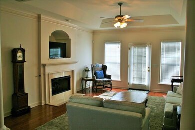 Spacious, bright, and neutral living room with gas fireplace and wood floors. 