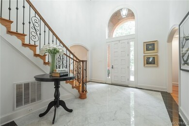 Tiled foyer with a high ceiling and sweeping stair
