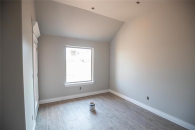 Spare room with wood finished floors and vaulted ceiling