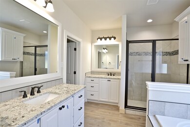 Full bathroom featuring a shower stall, wood finished floors, two vanities, recessed lighting, and a bathtub