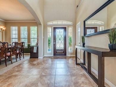 Foyer entrance with a chandelier, arched walkways, crown molding, light tile patterned floors, and a high ceiling