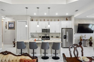 Kitchen with backsplash, appliances with stainless steel finishes, light stone counters, a kitchen breakfast bar, and light marble finish flooring
