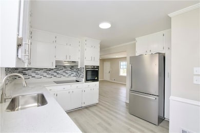 Kitchen with light countertops, a sink, white cabi