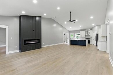 Unfurnished living room featuring ceiling fan, a large fireplace, light wood-style floors, recessed lighting, and high vaulted ceiling