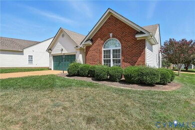 View of front of property featuring brick siding, a front yard, concrete driveway, and an attached garage