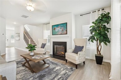 Living room with a glass covered fireplace, wood finished floors, and stairs