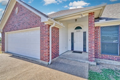 Property entrance with roof with shingles, brick siding, driveway, and an attached garage