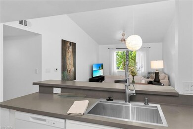 Kitchen with a sink, white dishwasher, open floor plan, dark countertops, and vaulted ceiling