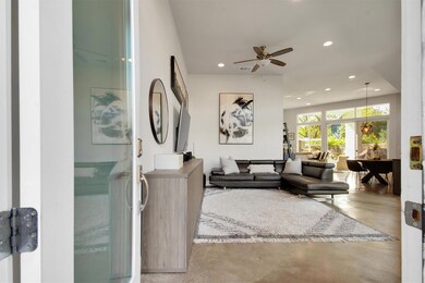 A bright, open-concept living and dining area with 14’ ceilings, polished concrete floors, and walls of windows that bring the outdoors in. Perfect for entertaining, relaxing, or enjoying the seamless flow from the kitchen to the private patio.