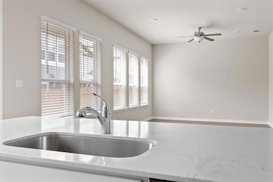 Kitchen with a sink, ceiling fan, and light stone