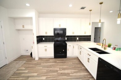 Kitchen featuring black appliances, tasteful backsplash, sink, light wood-type flooring, and white cabinets