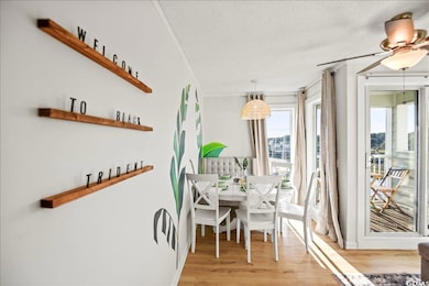 Dining space featuring light wood finished floors, a textured ceiling, crown molding, and ceiling fan