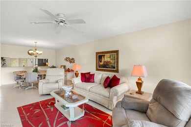 Living room featuring ceiling fan with notable chandelier and light tile patterned floors