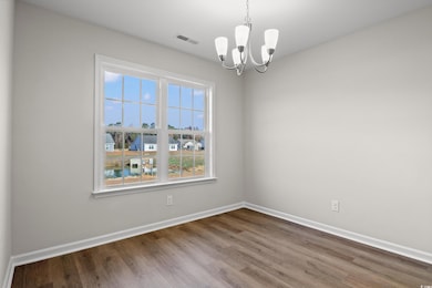 Empty room with a chandelier, wood finished floors