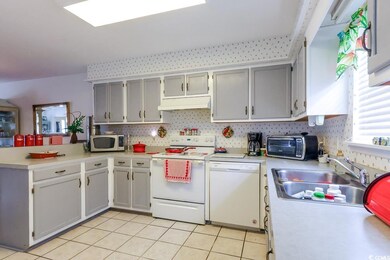 Kitchen with white appliances, a sink, a peninsula, and light countertops