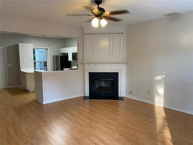 Welcome Home to your new living room featuring a ceiling fan, light wood-style flooring, a glass covered fireplace