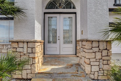View of exterior entry with stucco siding and ston