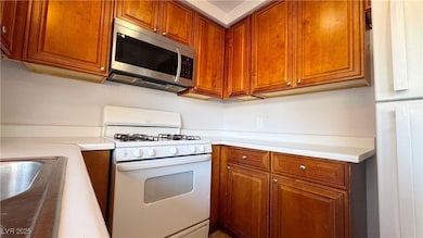 Kitchen with gas range gas stove, brown cabinets, and stainless steel microwave