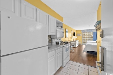 Kitchen featuring white appliances, light tile patterned floors, white cabinets, light countertops, and a textured ceiling