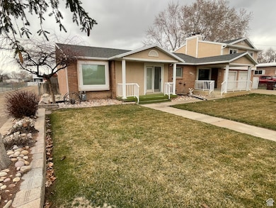 View of front of home featuring brick siding, a chimney, covered porch, a front yard, and stucco siding